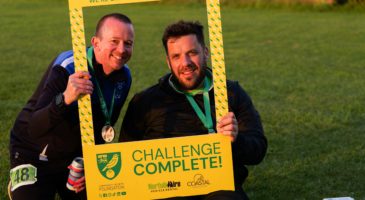 two men posing with 'challenge complete' sign