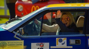 woman in sunglass waving from a car