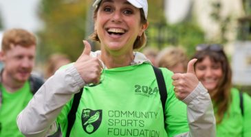 woman with white cap and green tshirt holding her thumbs up