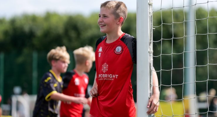 boy in red shirt standing by football goal