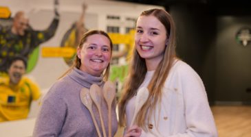 Two women holding wooden spoons