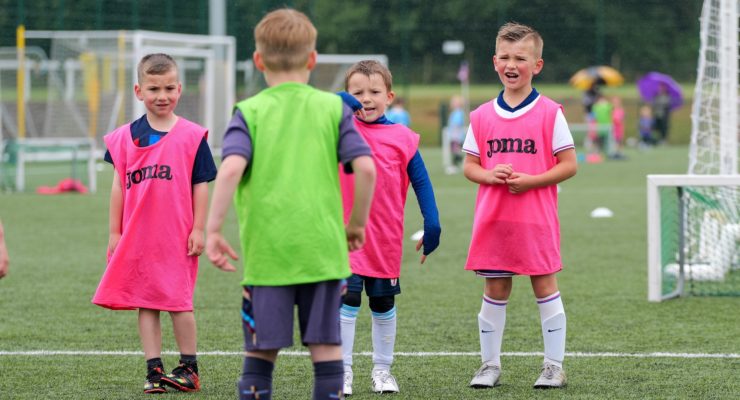 Children in Joma bibs playing football