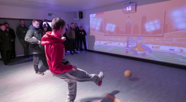 Boy kicking ball at a wall