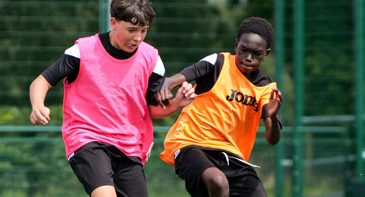 Two youth football players tackling the ball at The Nest.